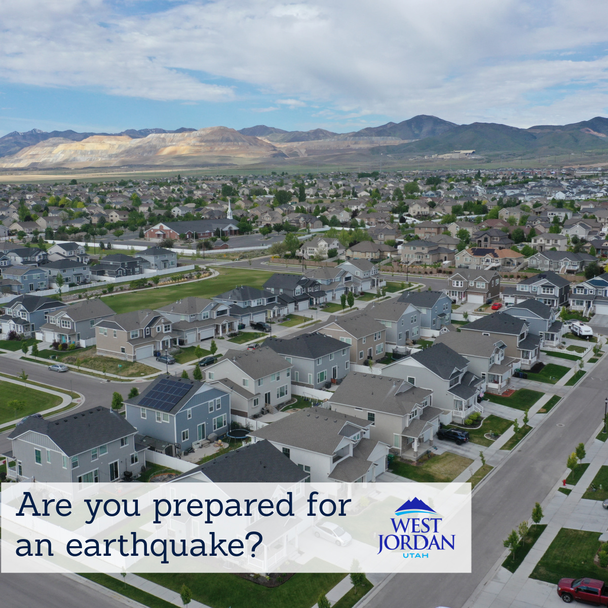 A suburban neighborhood with rows of houses, green spaces, and mountains in the background. Text reads, Are you prepared for an earthquake? with a logo for West Jordan, Utah.