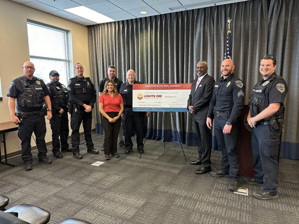 West Jordan Police Officers and partners with the new Lights On! Initiative pose in front of a ticket voucher