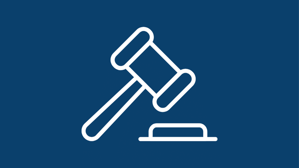 A white outline of a judges gavel striking a sound block on a dark blue background.