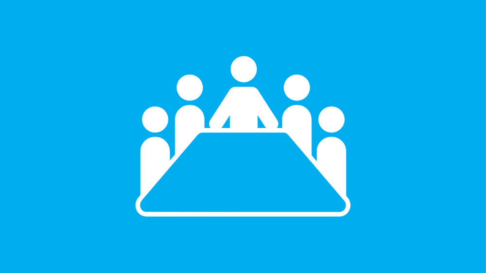 Icon of five abstract people sitting around a table on a blue background, with one person positioned at the head of the table, suggesting a meeting or group discussion.