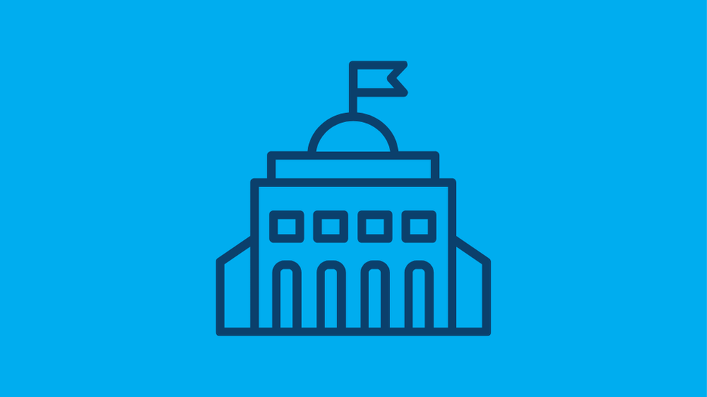 Simple line drawing of a government building with a domed roof and flag on top, set against a solid blue background.