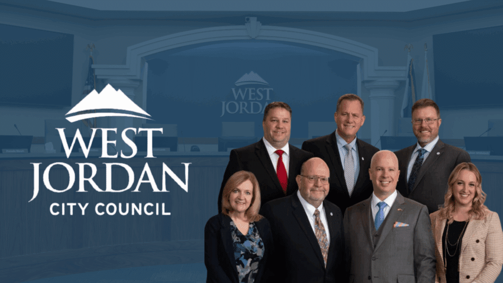 Seven people in business attire stand in front of a council chamber backdrop with “West Jordan City Council” and a mountain logo displayed on the left side of the image.