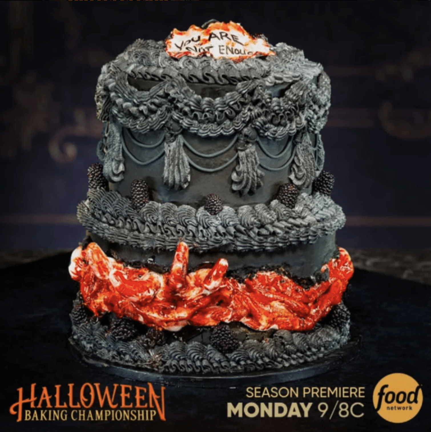 A two-tiered black cake decorated with gothic-style frosting, blackberries, and realistic-looking bloody severed fingers. The top features a message on white fondant. Text reads: Halloween Baking Championship, Season Premiere Monday 9/8c, Food Network.